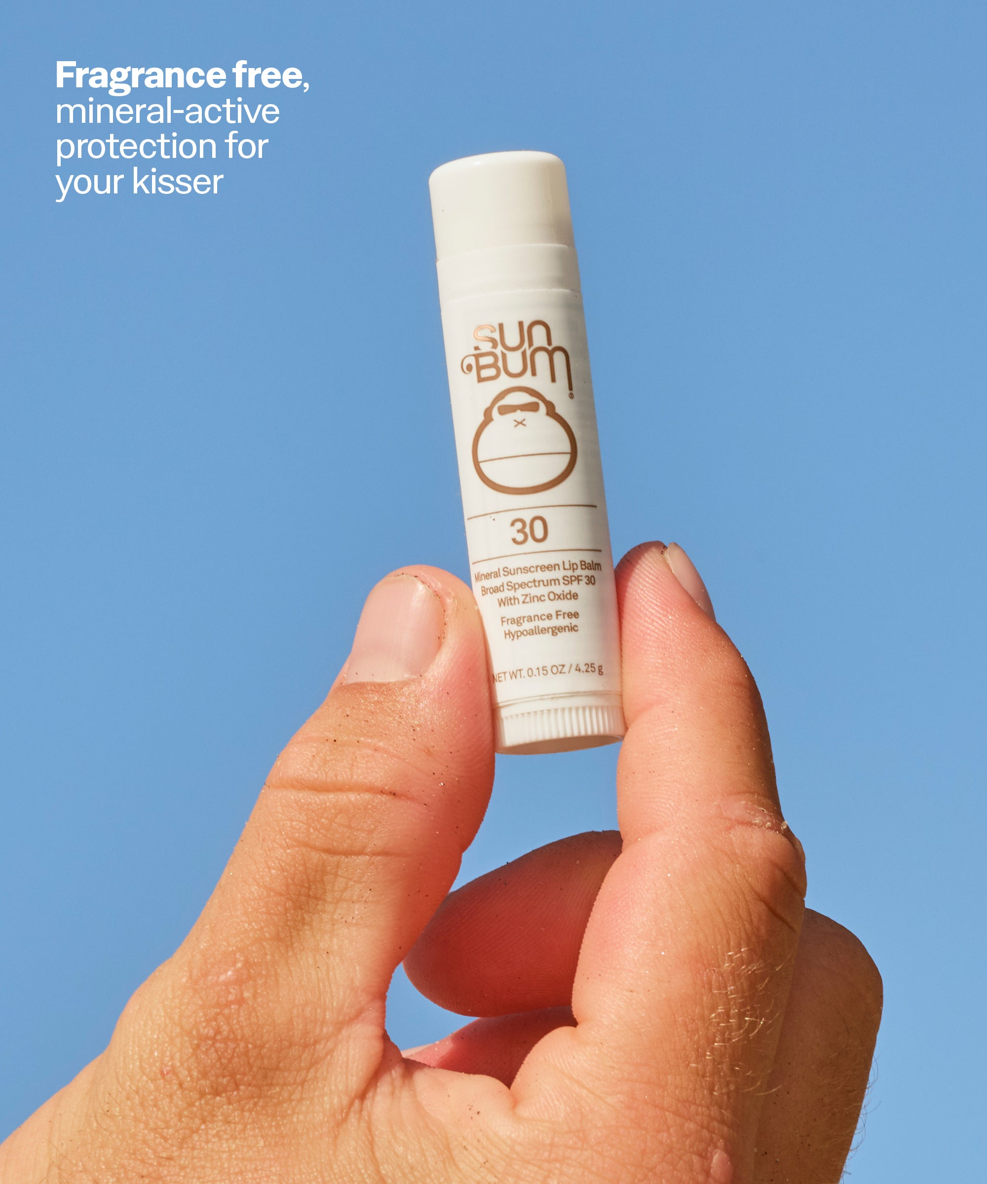 Hand holding a Sun Bum lip balm against a blue background