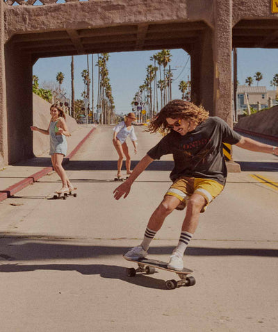 3 people on skateboards under a bridge