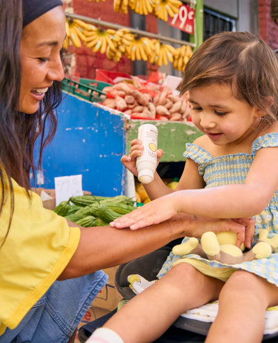 Woman and child at a market with produce in the background