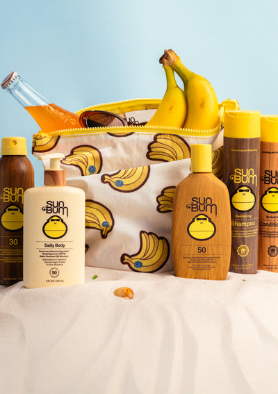 Sun Bum skincare and hair care products with a banana-themed pouch on a light blue background.