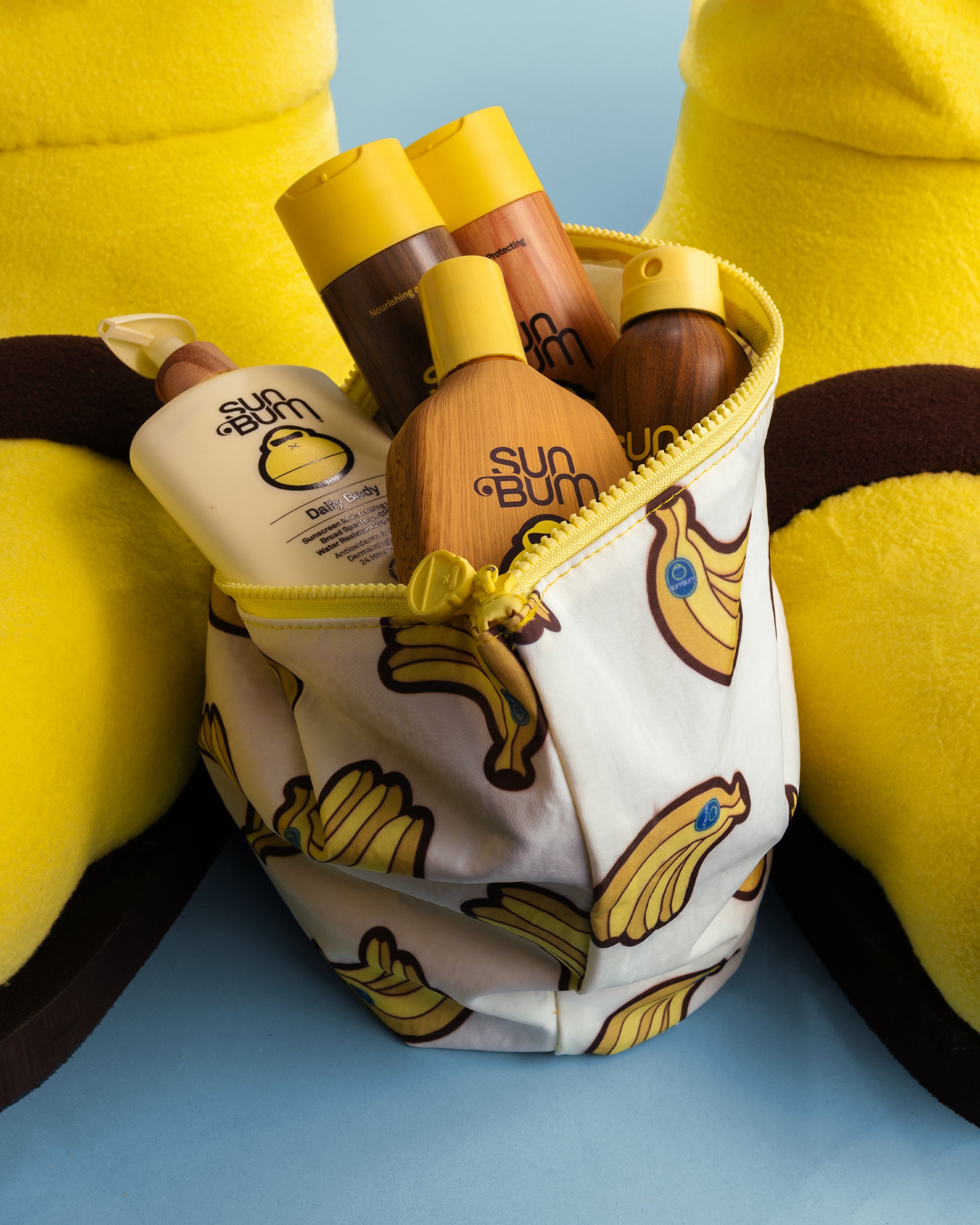 Sun Bum sunscreen products in a pouch with banana pattern on a blue background