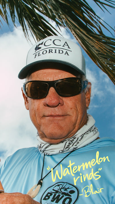 Man wearing a cap with 'CCA Florida' and sunglasses, standing under a palm tree with a blue sky.