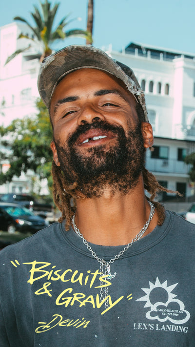 Man wearing a shirt with 'Biscuits & Gravy' text and a logo, standing outdoors.