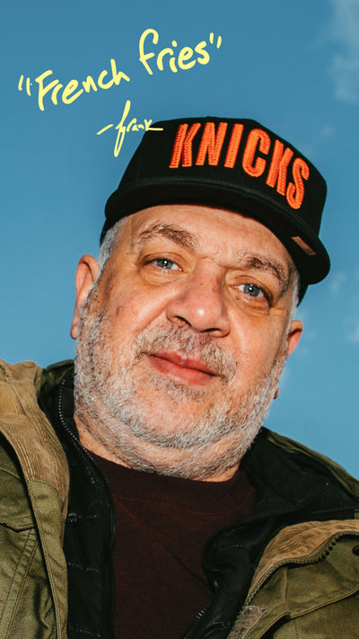 Man wearing a cap with 'Knicks' text against a blue sky
