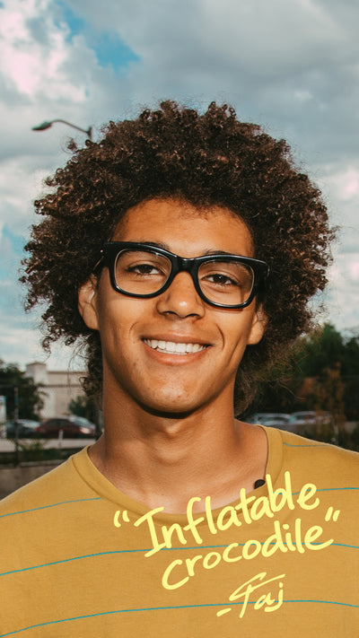Person wearing glasses and a yellow striped shirt with text, outdoors.