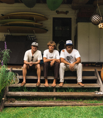 3 guys sitting on wooden deck stairs with green grass below