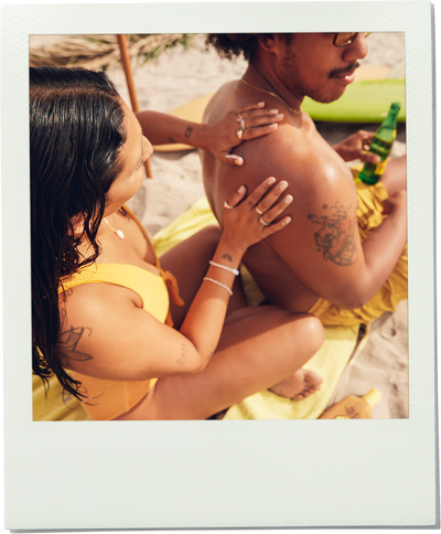 Two people on a beach with one person holding a bottle.
