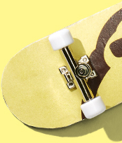 Close-up of a skateboard with a yellow deck and white trucks on a yellow background